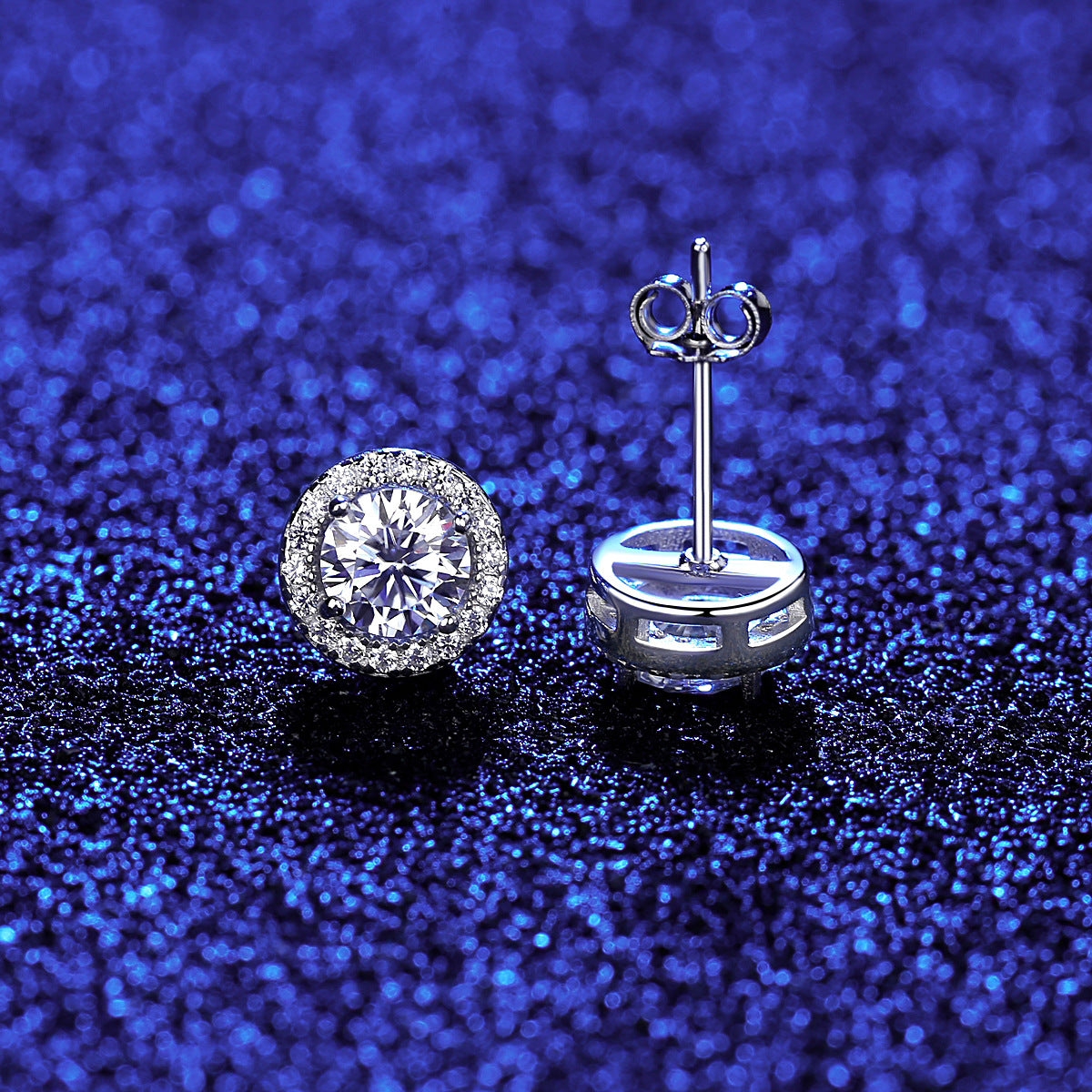Close-up of a diamond stud earring on a glittery blue background.